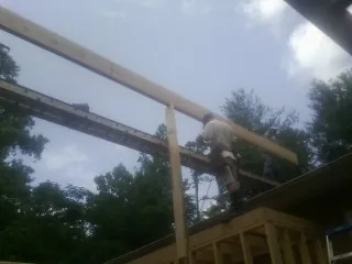 Carpenter setting a ridge beam over a new addition frame — Ice Dam Removal by Roofing Brothers in Olive Branch