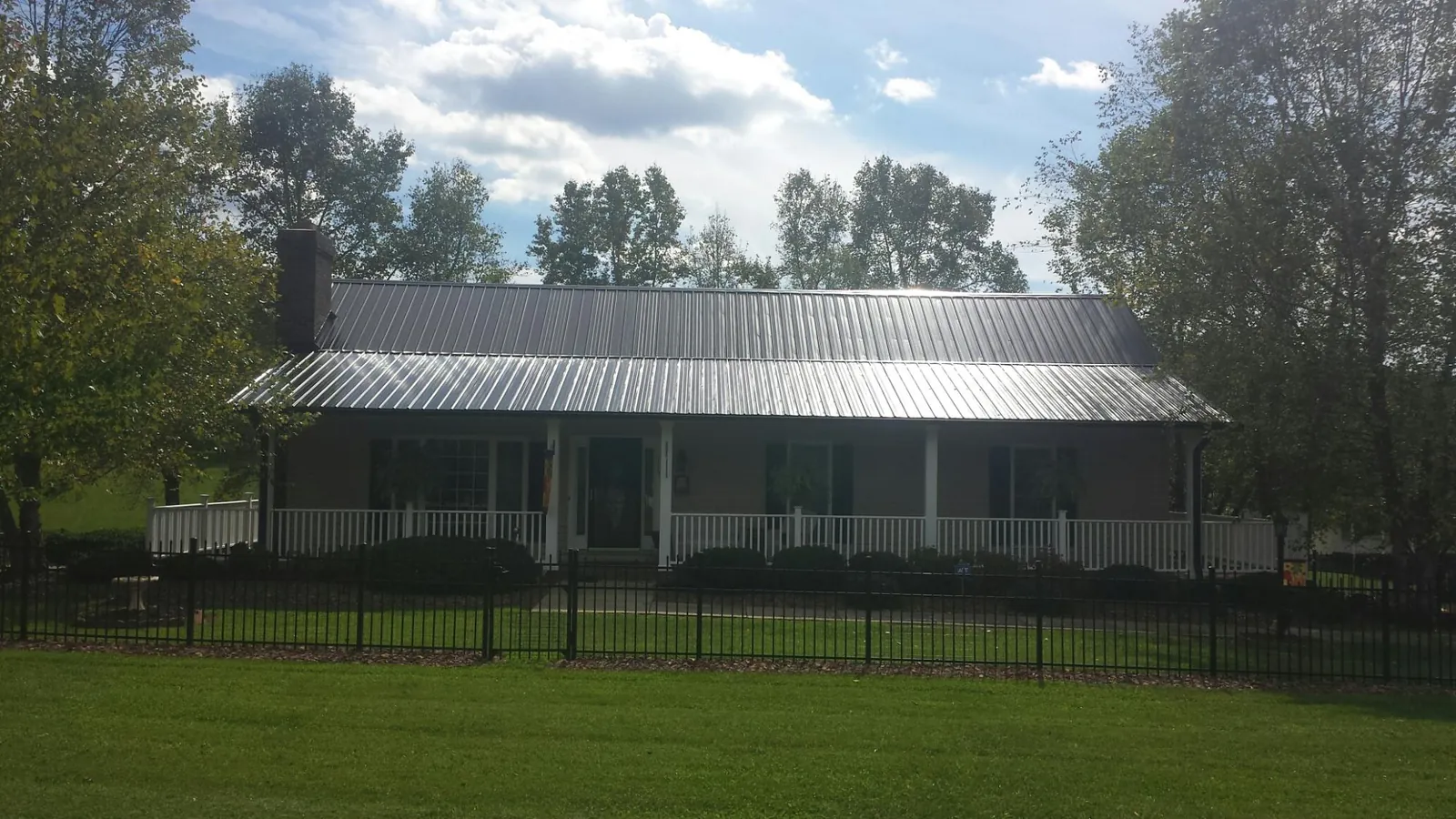 Gray metal roof on a brick ranch with a full width front porch — Gutter Guard Installation work by our crew in Olive Branch