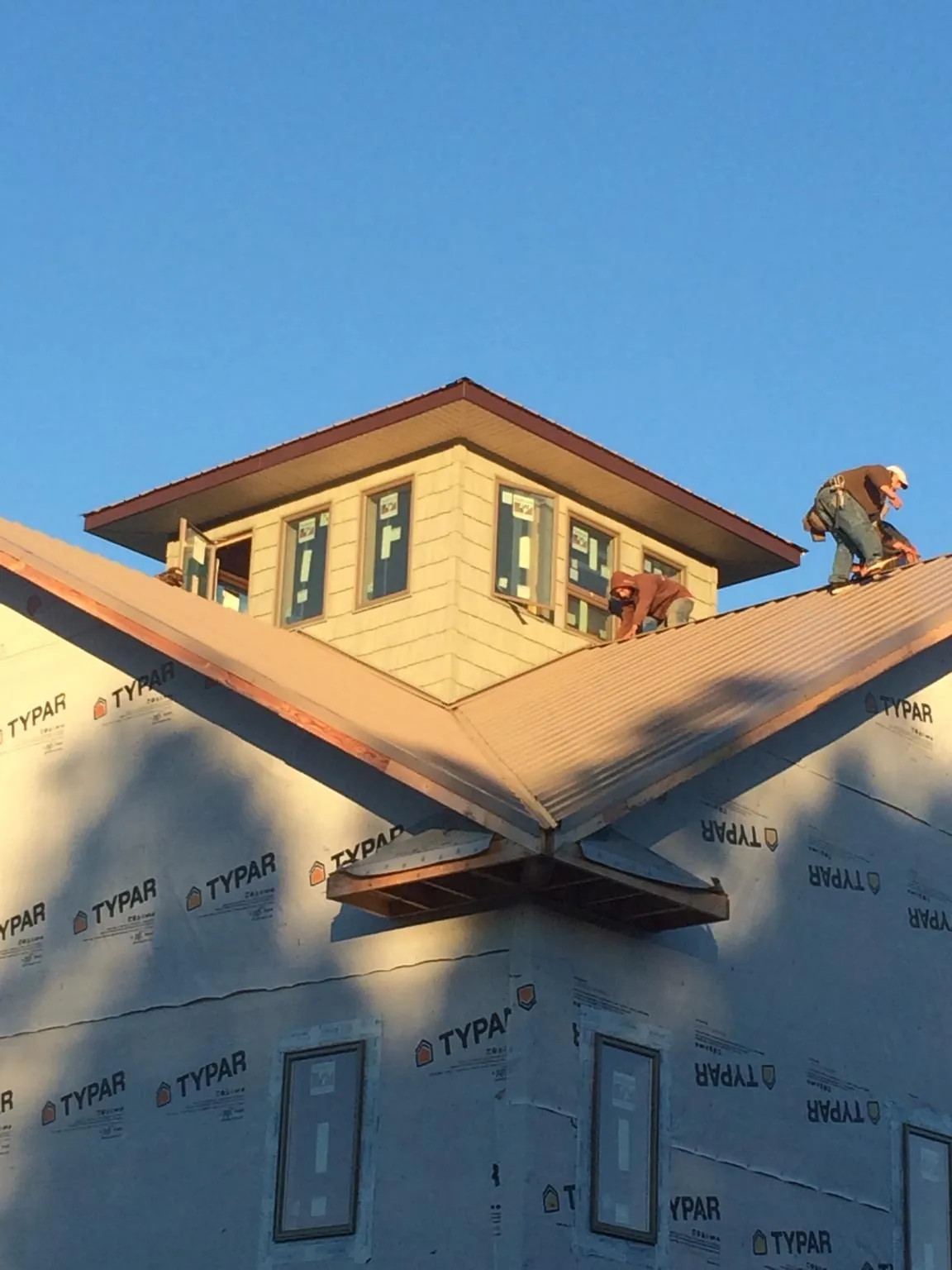 Roofers working around a rooftop cupola on a new metal roof at sunset — Roof Waterproofing in Olive Branch by Roofing Brothers